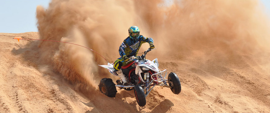An ATV racer kicks up major sand in a race