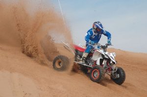 An ATV racer lands and kicks up dirt behind them