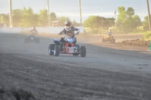 The winning ATV racer pushes the ATV off to the side of the track