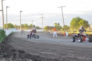 Four ATVs race around the bend with another close behind as an official waves a checkered flag