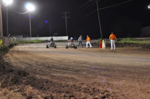 Two ATV racers head around the track at night