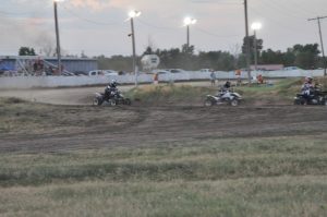 Three ATVs race on a dirt track