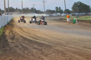 Three ATVs closely follow one another on a dirt track
