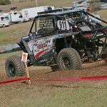 JSR Performance UTV number 911 races up a dirt track at a competition