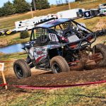 The JSR Performance UTV, number 911 kicks up dirt with its back tires as it races down the dirt track